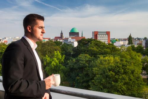 a man in a suit holding a cup of coffee at Mercure Hotel Hannover Mitte in Hannover