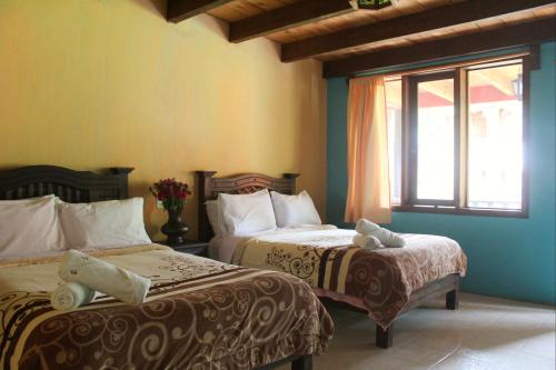 a bedroom with two beds and a window at Hotel Campestre Las Flores in San Cristóbal de Las Casas