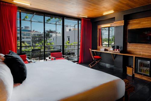 a bedroom with a bed and a desk and windows at Reina Roja Hotel Boutique in Playa del Carmen