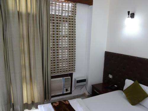 um quarto de hotel com uma cama e uma janela em Rams Inn em Nova Deli