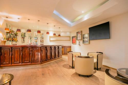 a bar with wooden cabinets and a flat screen tv at JOIA Rose Hall by Iberostar - Adults Only All Inclusive Resort in Montego Bay