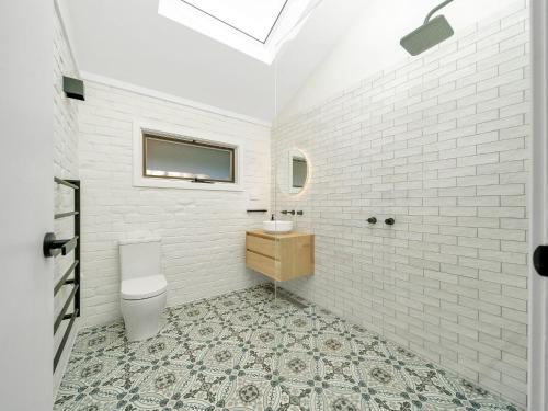 een witte badkamer met een wastafel en een toilet bij Saddleback Grove Kiama in Kiama