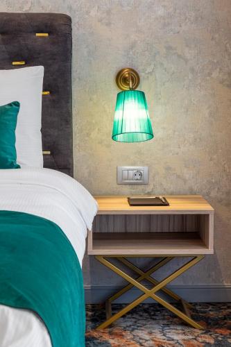 a green lamp on a table next to a bed at Tomis Garden Aparthotel Bucuresti in Bucharest