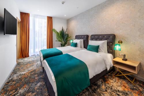 a hotel room with a large bed and a television at Tomis Garden Aparthotel Bucuresti in Bucharest