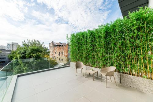 a balcony with chairs and a green wall at Tomis Garden Aparthotel Bucuresti in Bucharest