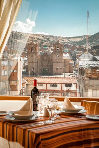 a table with a bottle of wine and a view of a city at Hotel Hacienda Puno Centro Histórico in Puno