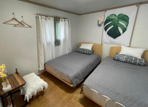 a bedroom with two beds and a table with a table at Saesori Guesthouse in Gangneung