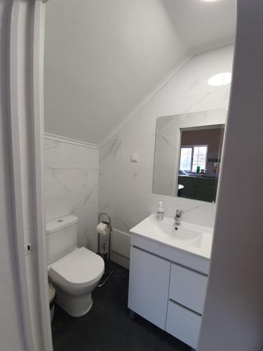 a white bathroom with a toilet and a sink at Casa Baptista in Monchique