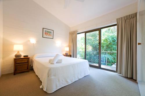 a bedroom with a white bed and a large window at Caralina Court in Noosa Heads