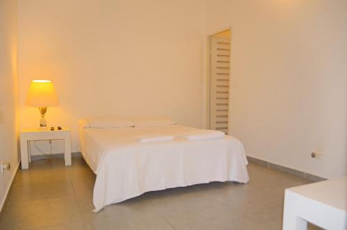 a white bed in a white room with a lamp at Casamarilla in Mariquita