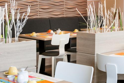 a dining room with a table and white chairs at ibis Styles Arnsberg - Neheim in Arnsberg
