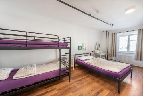 2 camas en una habitación con literas de color púrpura en AdHoc Hostel en Liubliana