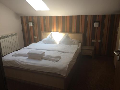 a bedroom with a white bed with towels on it at Pensiunea JOJO in Băile Herculane