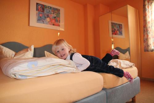 a little girl laying on top of a bed at Hotel-Pension Grüne Linde in Delitzsch