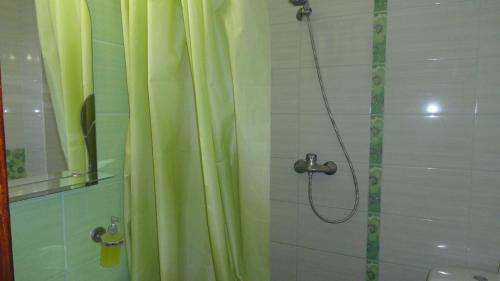 a shower with a yellow shower curtain in a bathroom at Guest House Romashka in Feodosia