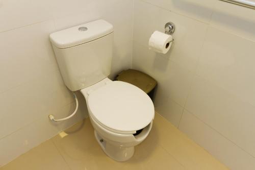 a white toilet in a bathroom with a roll of toilet paper at Pleione Flats in Curitiba