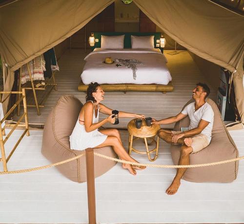 a man and a woman sitting in a tent at Autentik Penida "Glamping" - Adults only in Nusa Penida