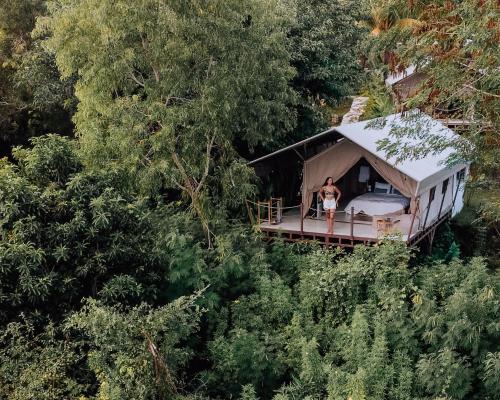 a man standing on the porch of a house in the forest at Autentik Penida "Glamping" - Adults only in Nusa Penida