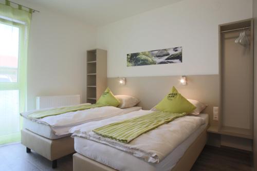 two beds with green pillows in a room at Smart Motel in Gars am Kamp