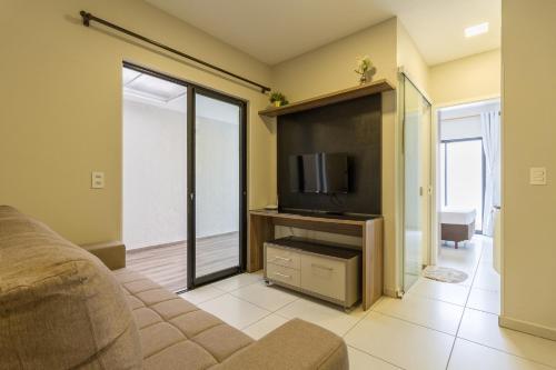 a living room with a couch and a flat screen tv at Pleione Flats in Curitiba