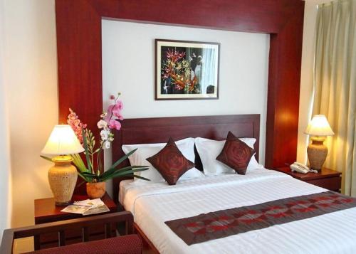 a hotel room with a bed and two lamps and flowers at Sabaidee@Lao Hotel Vientiane in Vientiane