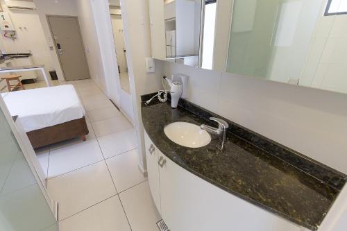 a bathroom with a sink and a bed in a room at Pleione Flats in Curitiba