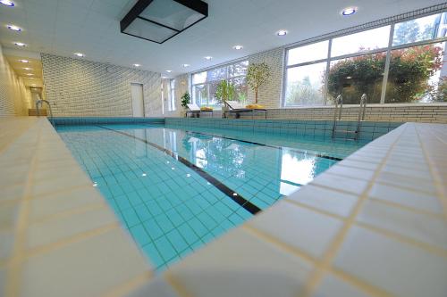 - une grande piscine revêtue de carrelage bleu dans l'établissement Hotel und Kongresszentrum Wanderath, à Baar