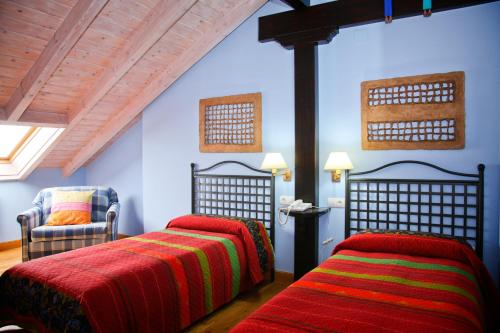a bedroom with two beds and a chair at Posada Casona de la Ventilla in Laredo