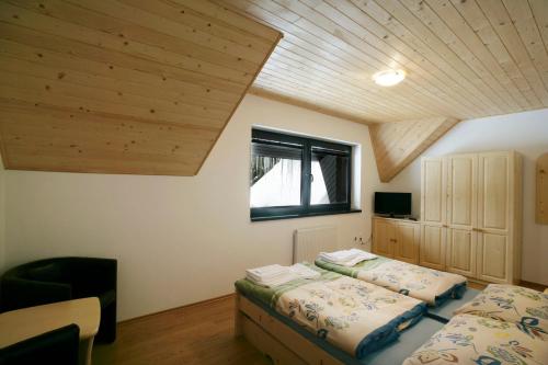 two beds in a bedroom with a wooden ceiling at Penzión Kohútik in Oravská Lesná