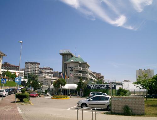 a parking lot with cars parked in front of a building at Hotel Palacio del Mar in Santander