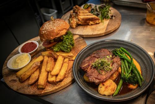 a table with plates of food with a hamburger and french fries at The Amberley Hotel in Amberley