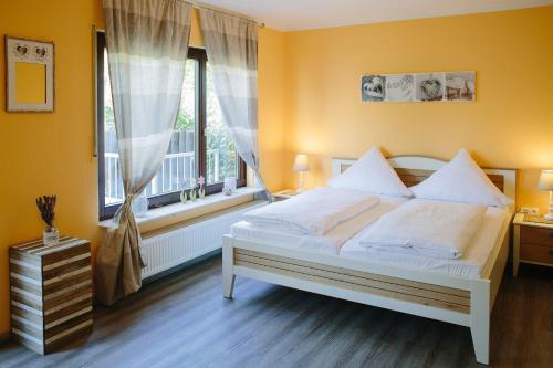 a bedroom with a white bed and a window at Gästehäuser Kappelmühle in Grünstadt