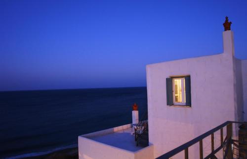 a white building with a window next to the ocean at Antigoni in Skiros