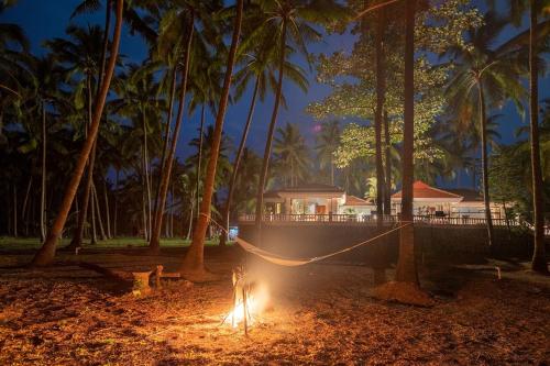 a fire pit in front of a house with palm trees at Casa Del Mer by StayVista - Nearby beach with, sea-view rooms & coconut farm in Alibaug