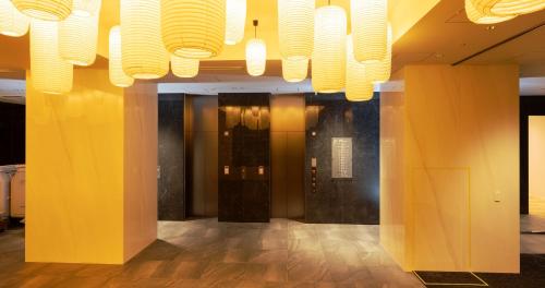 a lobby with yellow walls and a chandelier at HOTEL SANSUI NAHA Ryukyu Onsen Naminoue-No-Yu in Naha