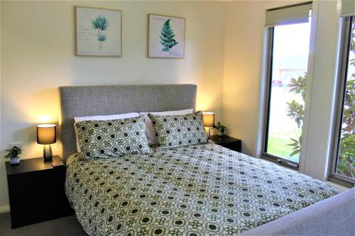 a bedroom with a bed and two lamps and a window at Clearwaters Albury in Albury