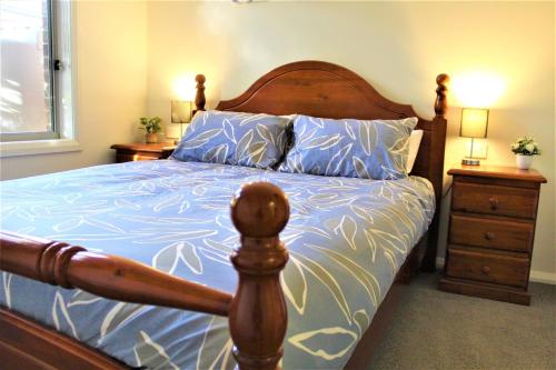 a bedroom with a wooden bed with blue and white sheets at Clearwaters Albury in Albury