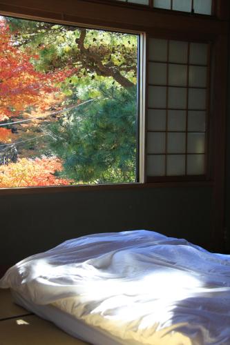 an unmade bed in front of a window at Atami Roji Kaede -熱海 路地楓- 温泉付 ペット可 in Atami