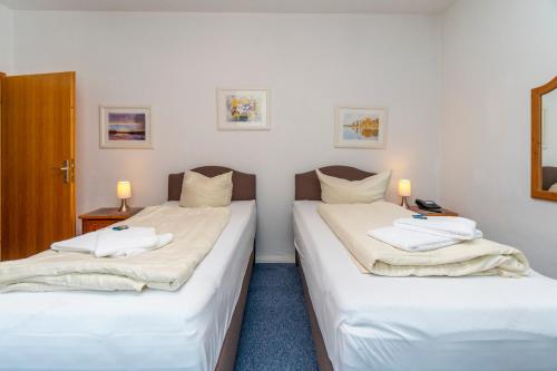 two twin beds in a room with white walls at Hotel Holsteinische Schweiz am Dieksee in Malente