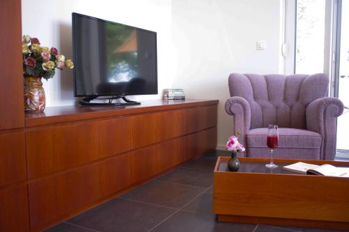 a living room with a tv and a chair at Guest House Villa Dagmar in Crikvenica