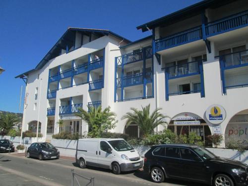 a white building with cars parked in front of it at Résidence Mer & Golf Sokoburu in Hendaye