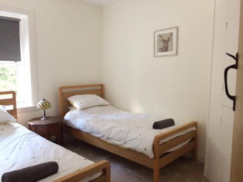 a bedroom with two beds and a window at Birchwood Cottage - In the Heart of Wooler in Wooler