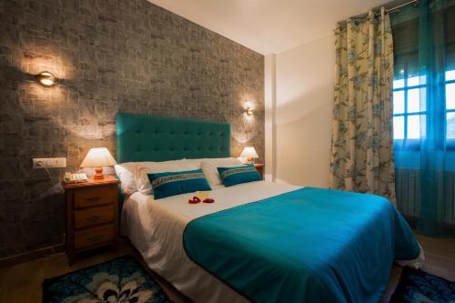 a bedroom with a large bed with a blue headboard at Hotel & Apartamentos Cons da Garda in San Vicente de O Grove