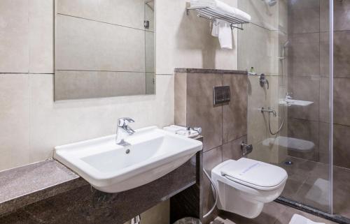 a bathroom with a sink and a toilet and a shower at Sai International Hotel in Dāvangere