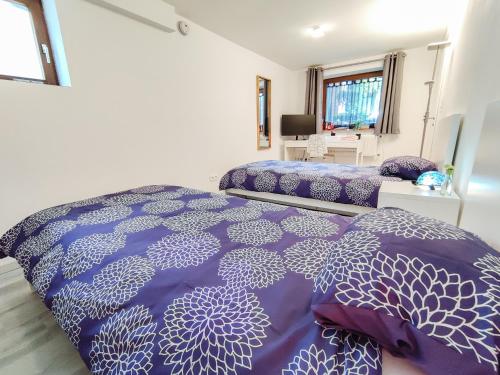 - une chambre avec 2 lits avec des draps violets et blancs dans l'établissement Tranquil City Haven close to Airport & Basel, à Saint-Louis