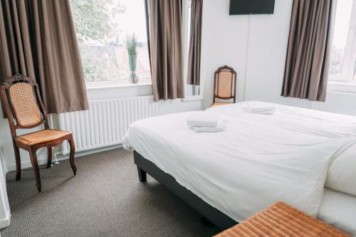 a bedroom with a bed and a chair and a window at Hotel Café Restaurant Abina in Amstelveen