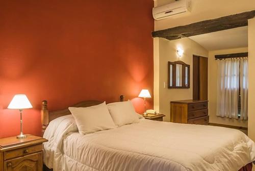 Gran Hotel Nono في نونو: غرفة نوم مع سرير أبيض كبير مع جدران برتقالية