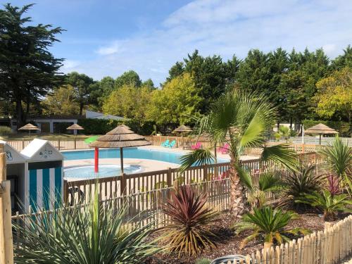 a pool at a resort with a fence and palm trees at Camping Les Maraises in Saint-Martin-de-Ré