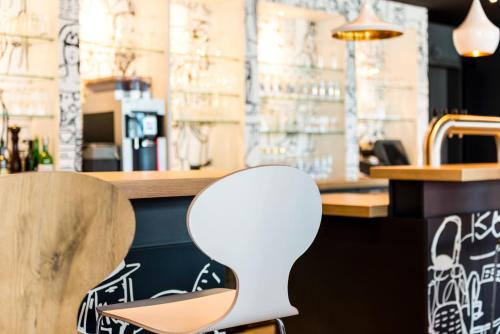 a white chair sitting in front of a bar at ibis Hotel München Garching in Garching bei München