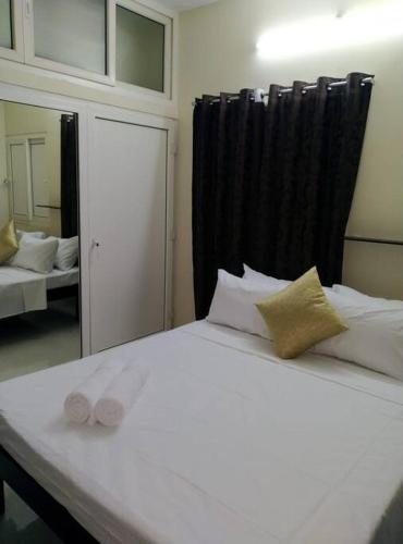 a bedroom with a white bed with a mirror at Aarudhara Holiday Home (A Home away from Home) in Puducherry
